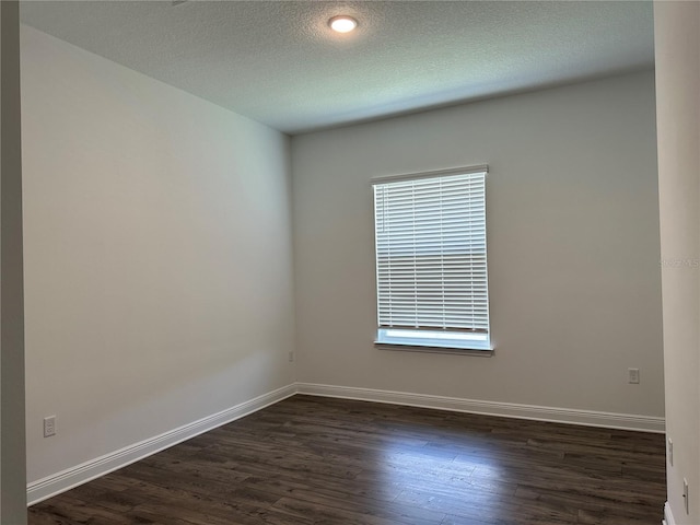 unfurnished room with dark wood-style floors, a textured ceiling, and baseboards