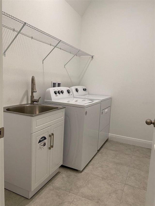 clothes washing area with separate washer and dryer, baseboards, and cabinet space
