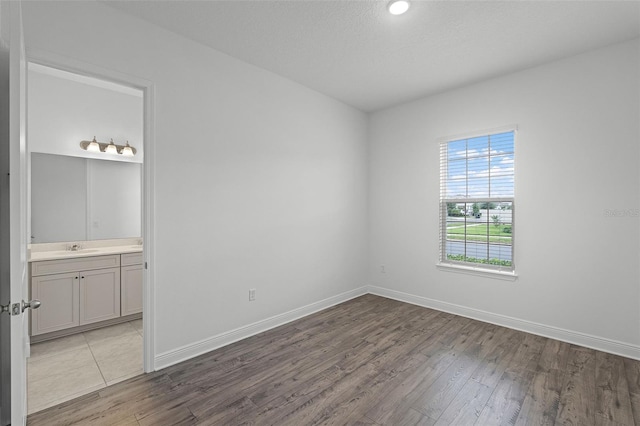 15161 Lake Bessie Loop, Winter Garden, FL 34787 - unfurnished bedroom with wood finished floors, a sink, and baseboards