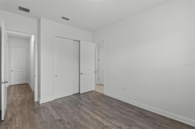 15161 Lake Bessie Loop, Winter Garden, FL 34787 - unfurnished bedroom featuring dark wood finished floors, baseboards, and a closet