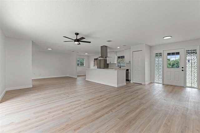 7085 Willowwood St, Orlando, FL 32818 - unfurnished living room featuring a sink, light wood finished floors, baseboards, a ceiling fan, and a textured ceiling