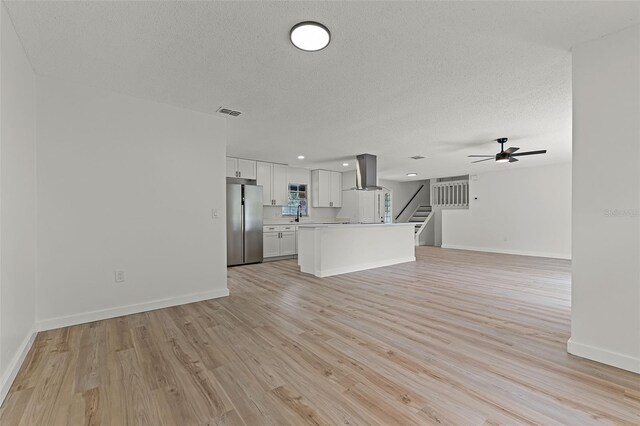 7085 Willowwood St, Orlando, FL 32818 - unfurnished living room featuring stairs, ceiling fan, a textured ceiling, light wood finished floors, and baseboards
