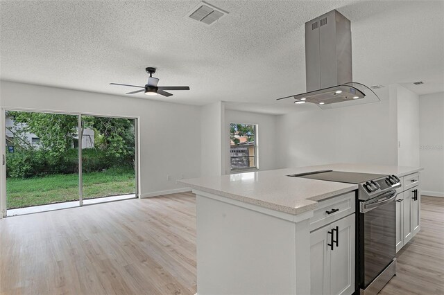 7085 Willowwood St, Orlando, FL 32818 - kitchen with electric stove, island range hood, light wood-type flooring, ceiling fan, and baseboards