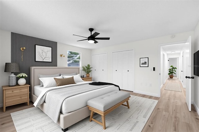 7085 Willowwood St, Orlando, FL 32818 - bedroom featuring two closets, baseboards, light wood-type flooring, and ceiling fan