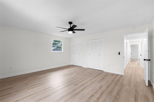 7085 Willowwood St, Orlando, FL 32818 - unfurnished bedroom with multiple closets, light wood-style flooring, baseboards, ceiling fan, and a textured ceiling