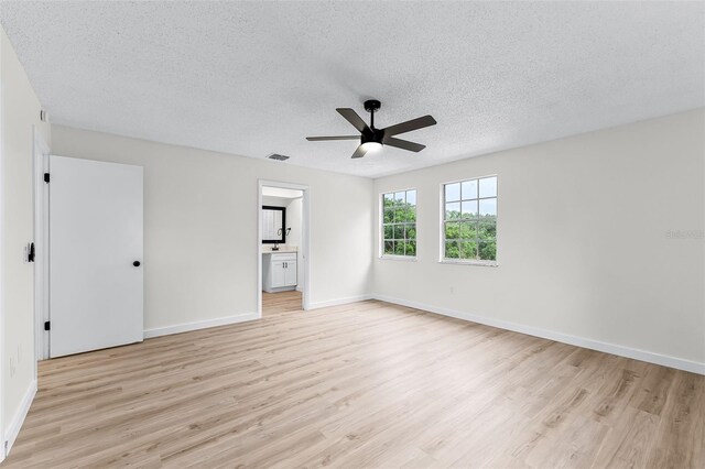 7085 Willowwood St, Orlando, FL 32818 - unfurnished bedroom with light wood-style flooring, a textured ceiling, baseboards, ensuite bath, and ceiling fan