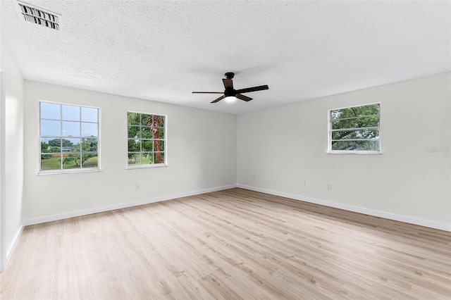 7085 Willowwood St, Orlando, FL 32818 - empty room with wood finished floors, a textured ceiling, plenty of natural light, a ceiling fan, and baseboards