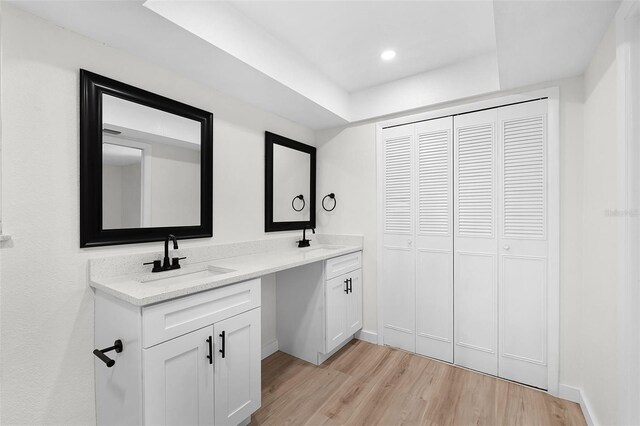 7085 Willowwood St, Orlando, FL 32818 - bathroom with a tray ceiling, wood finished floors, double vanity, and baseboards