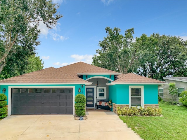 view of front of home with a garage, driveway, a front lawn, stucco siding, and roof with shingles