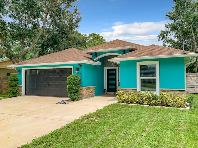 view of front facade featuring an attached garage, a front lawn, stucco siding, and concrete driveway