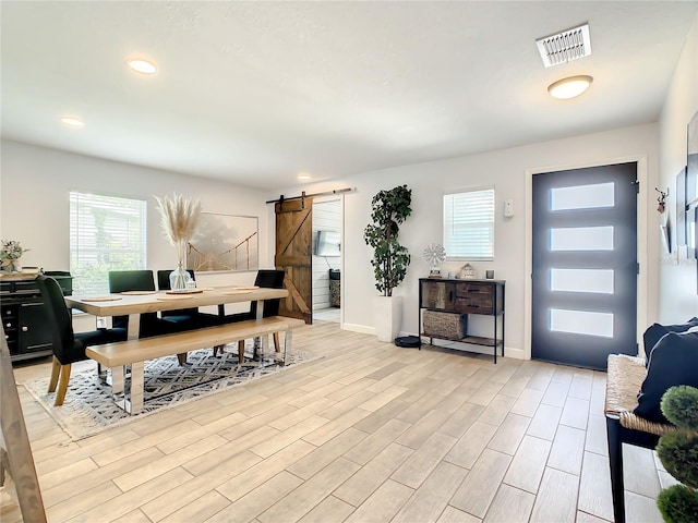 dining space with a barn door, light wood-style floors, baseboards, and recessed lighting