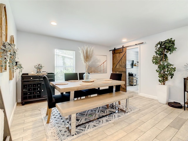 dining area featuring a barn door, light wood-style floors, recessed lighting, and baseboards