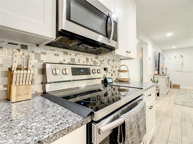 kitchen featuring stainless steel appliances, tasteful backsplash, white cabinetry, recessed lighting, and light stone counters