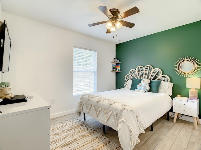 bedroom featuring baseboards, light wood-type flooring, and a ceiling fan
