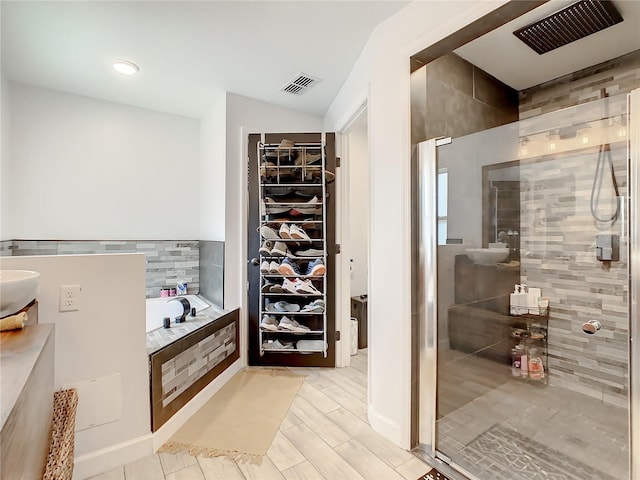 bathroom featuring a shower stall, a garden tub, and a walk in closet