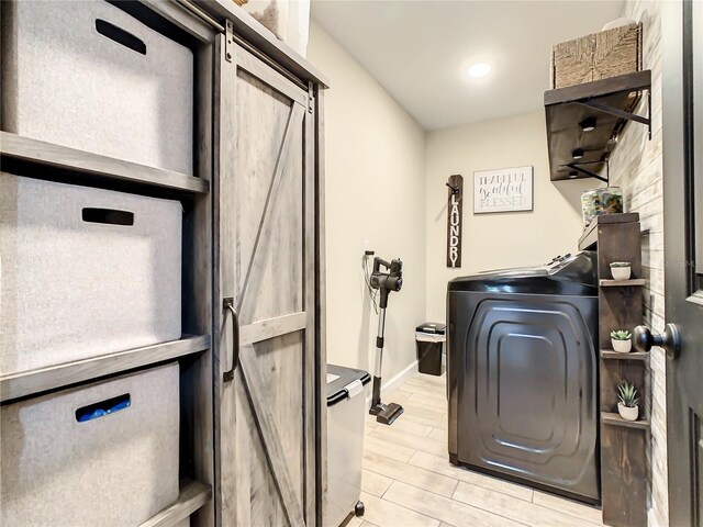 washroom with a barn door, washer / dryer, baseboards, recessed lighting, and light wood-style flooring
