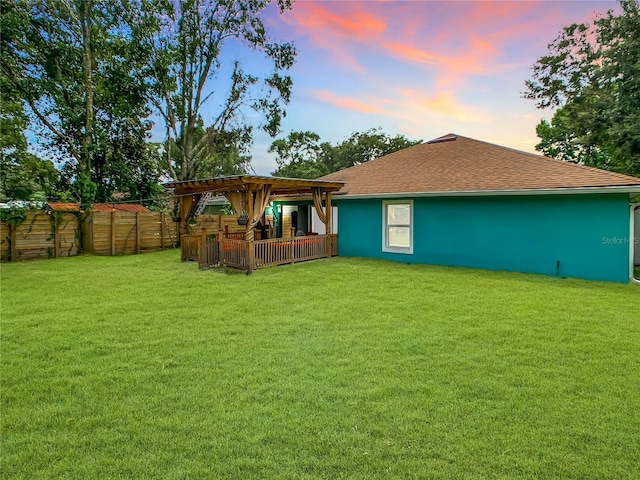 back of property at dusk with a shingled roof, a pergola, and stucco siding