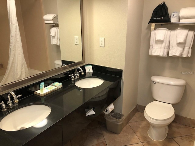 bathroom featuring toilet, baseboards, tile patterned flooring, double vanity, and a shower with shower curtain