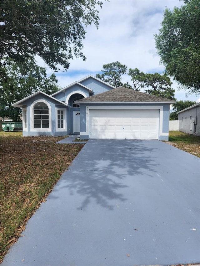 ranch-style house featuring stucco siding, driveway, and an attached garage