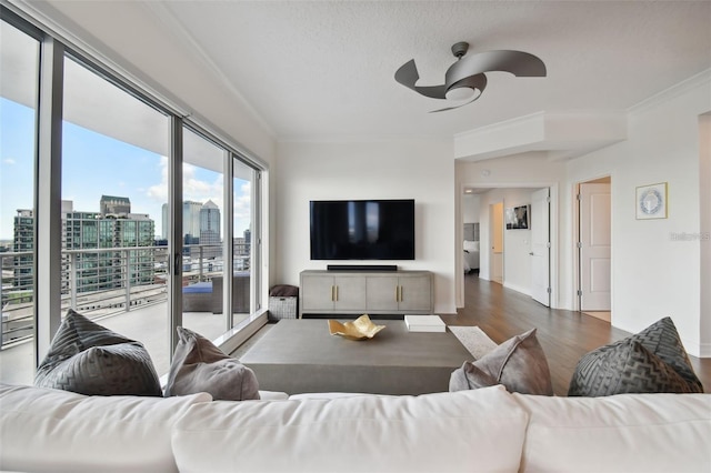 living area featuring a ceiling fan, ornamental molding, and wood finished floors