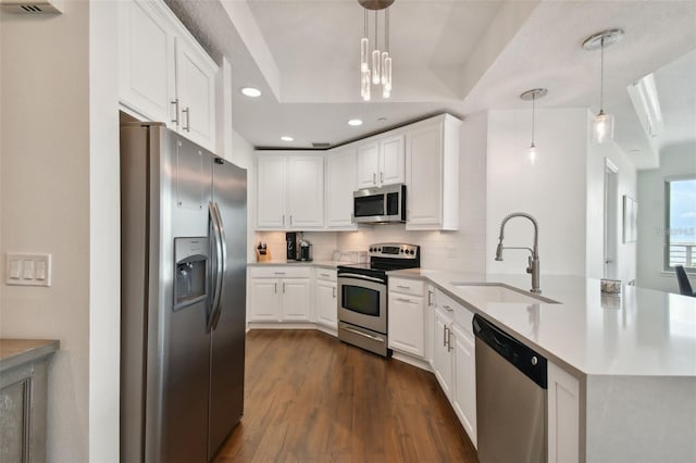 kitchen with appliances with stainless steel finishes, a sink, a peninsula, backsplash, and recessed lighting