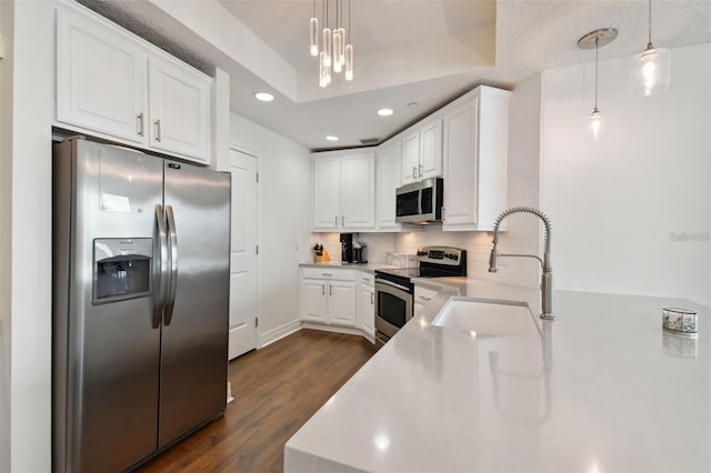kitchen featuring appliances with stainless steel finishes, a sink, dark wood-style flooring, tasteful backsplash, and light countertops