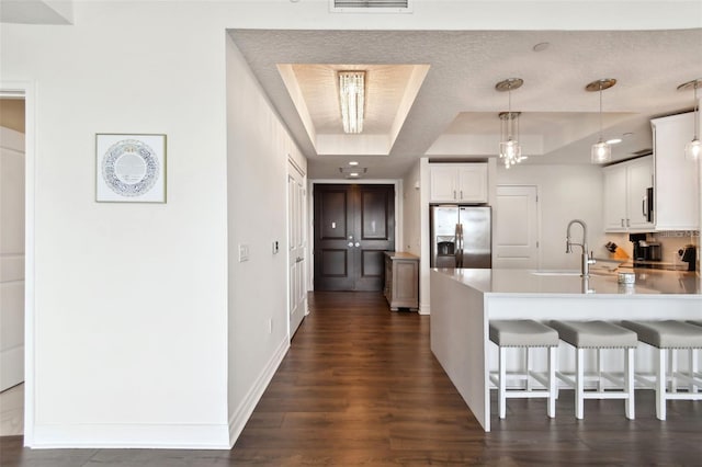 kitchen with stainless steel appliances, a raised ceiling, a sink, a peninsula, and dark wood-style floors