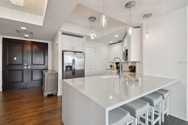 kitchen with stainless steel appliances, a textured ceiling, dark wood-style flooring, a peninsula, and white cabinets