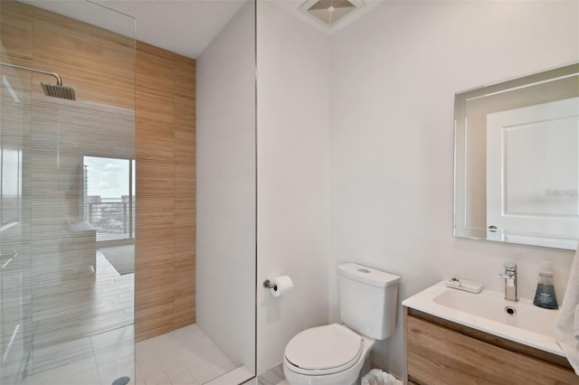 bathroom featuring tiled shower, toilet, and vanity