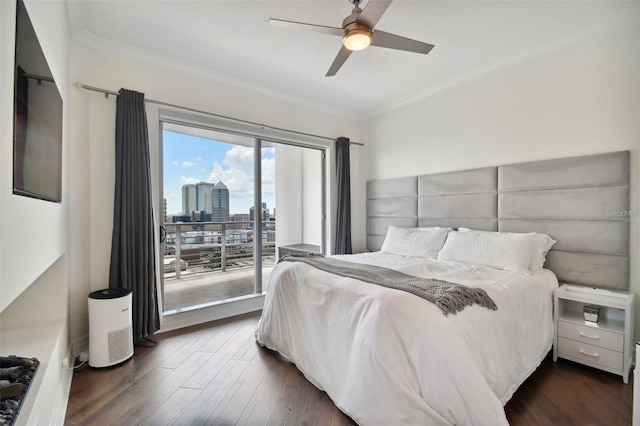 bedroom with access to outside, dark wood-type flooring, a city view, ceiling fan, and crown molding