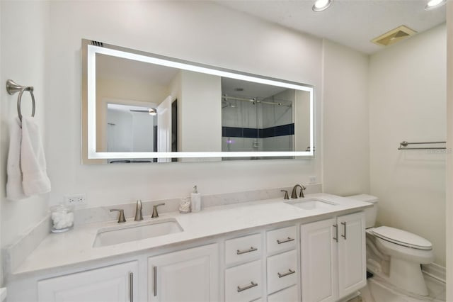 bathroom featuring toilet, recessed lighting, double vanity, and a shower