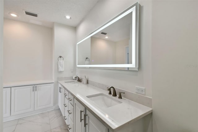 full bathroom featuring marble look tiles, double vanity, recessed lighting, and a textured ceiling