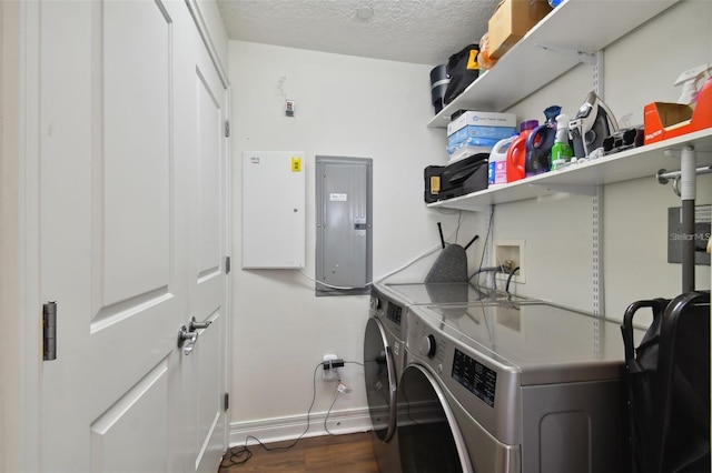 laundry area featuring washing machine and dryer, baseboards, wood finished floors, electric panel, and a textured ceiling