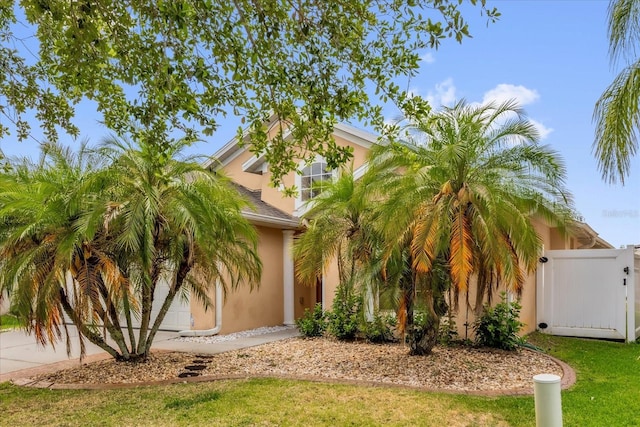 14617 Keelford Way, Orlando, FL 32824 - view of property hidden behind natural elements featuring stucco siding, a gate, and driveway