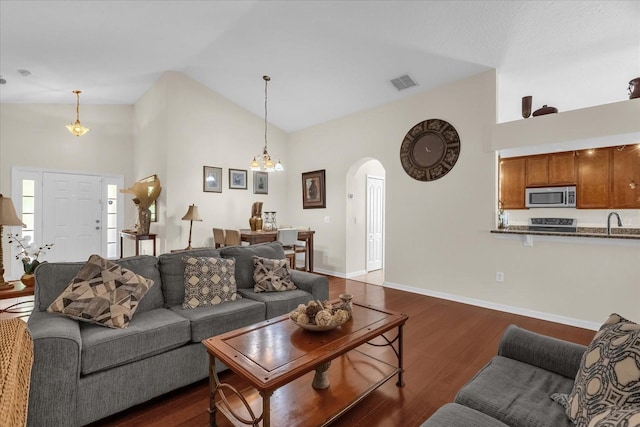 14617 Keelford Way, Orlando, FL 32824 - living room featuring arched walkways, dark wood finished floors, high vaulted ceiling, a chandelier, and baseboards
