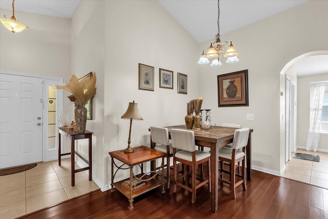 14617 Keelford Way, Orlando, FL 32824 - dining space featuring arched walkways, high vaulted ceiling, baseboards, wood finished floors, and a chandelier