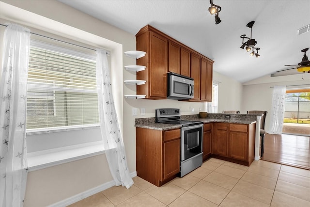 14617 Keelford Way, Orlando, FL 32824 - kitchen with stainless steel appliances, brown cabinetry, plenty of natural light, and lofted ceiling