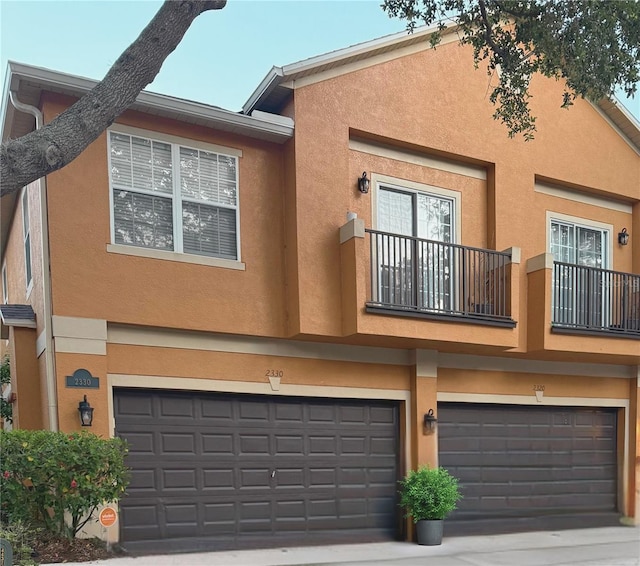 2330 Little Gem Loop, Sanford, FL 32773 - rear view of house with a balcony, stucco siding, a garage, and driveway