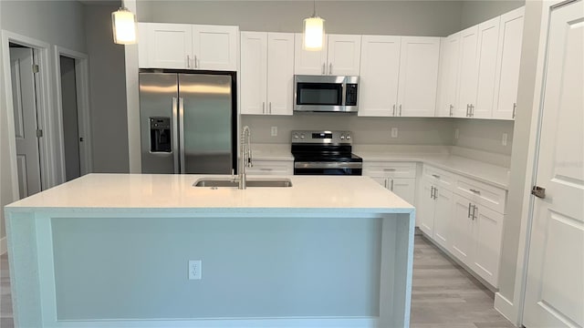 475 Marion Oaks Mnr, Ocala, FL 34473 - kitchen featuring stainless steel appliances, a sink, decorative light fixtures, white cabinetry, and light wood-type flooring