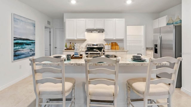 4908 Kaia Ave, Winter Haven, FL 33884 - kitchen with appliances with stainless steel finishes, under cabinet range hood, a sink, white cabinetry, and light tile patterned floors
