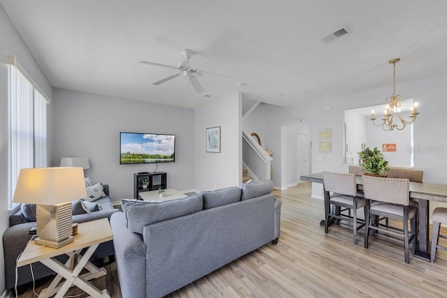 2706 Camaro Dr, Kissimmee, FL 34746 - living room featuring stairway, arched walkways, light wood finished floors, ceiling fan, and a chandelier