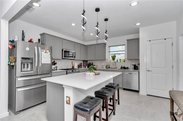 8413 SW 54th Loop, Ocala, FL 34481 - kitchen featuring stainless steel appliances, a sink, gray cabinets, a kitchen bar, and backsplash