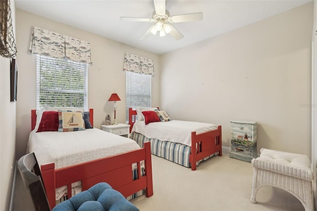 bedroom with multiple windows, light colored carpet, and a ceiling fan