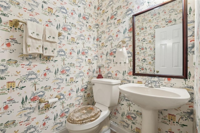 bathroom with wallpapered walls, baseboards, and toilet