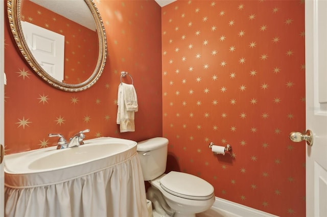 half bathroom featuring toilet, a sink, and baseboards