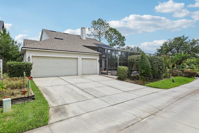 view of front of home featuring concrete driveway, a garage, stucco siding, and glass enclosure