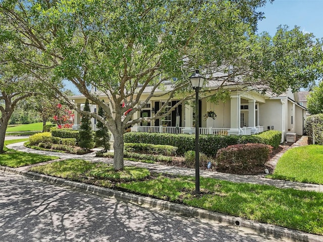 view of property hidden behind natural elements with a porch and stucco siding
