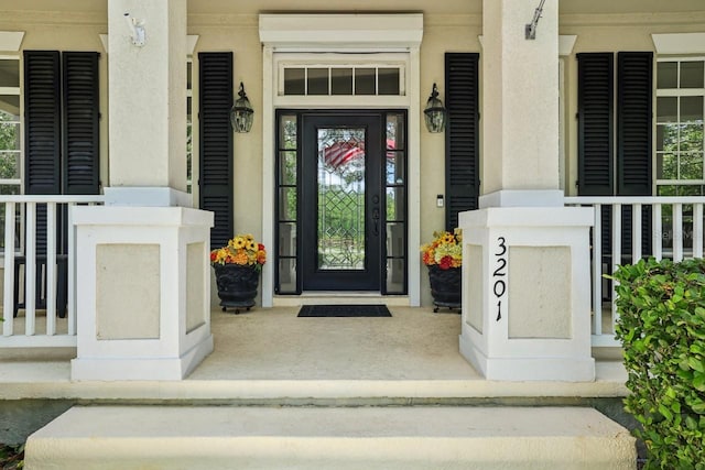 entrance to property featuring a porch and stucco siding