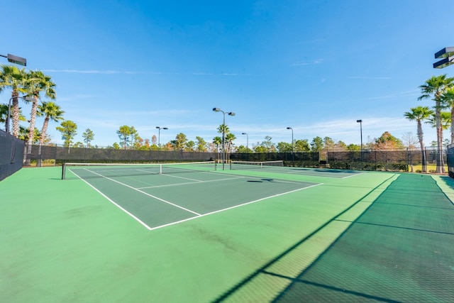 view of tennis court with community basketball court and fence