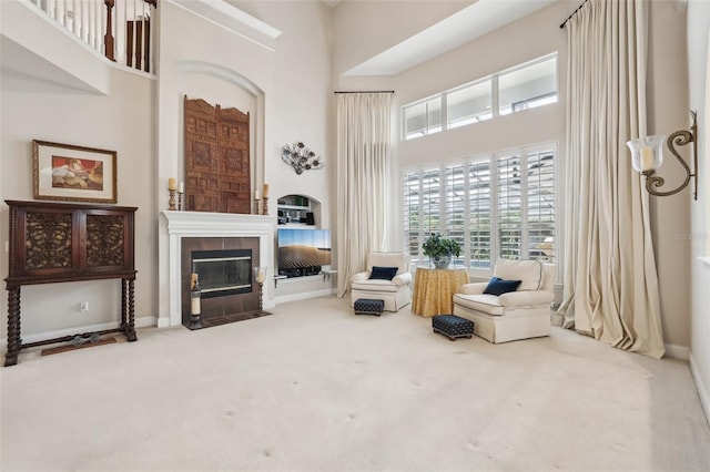 sitting room featuring a high ceiling, a fireplace, and carpet floors